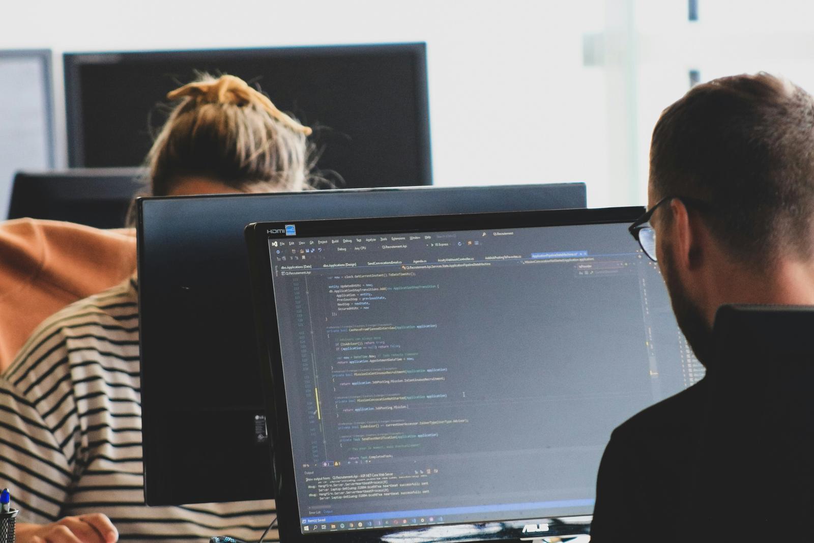 Software developers reviewing code together at their workstations